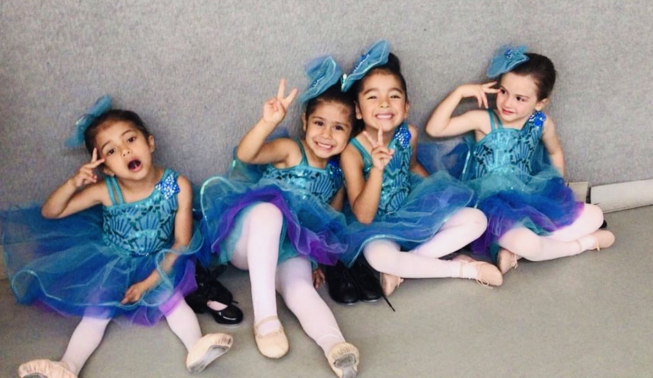 Young Children Sitting Side By Side In Teal Ballet Dresses